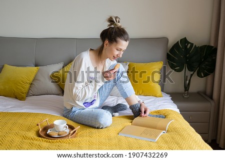 Millennial Caucasian woman with blonde hair relaxing on bed at home during coronavirus Covid-19 pandemic quarantine
