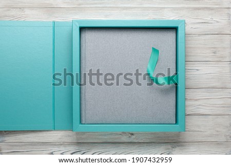 blue stylish square cardboard box for leather photoalbum.
Bright box with grey wedding album on wooden background
fabric family photo book in open box. wedding photobook in gift cardboard box