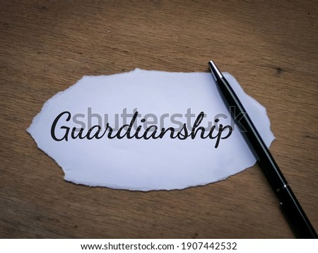 Selective focus top view text Guardianship written on a piece of paper with a pen.  Royalty-Free Stock Photo #1907442532