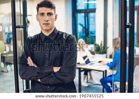 Portrait of businessman with crossed arms on background of office