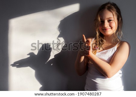 Girl shows dove symbol on the wall that she folded with her hands