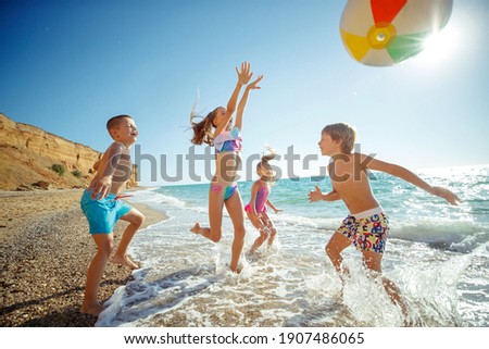 A group of children have fun playing at the sea. Children in bathing suits. Friends holding hands and running on the beach. High quality photo. Royalty-Free Stock Photo #1907486065