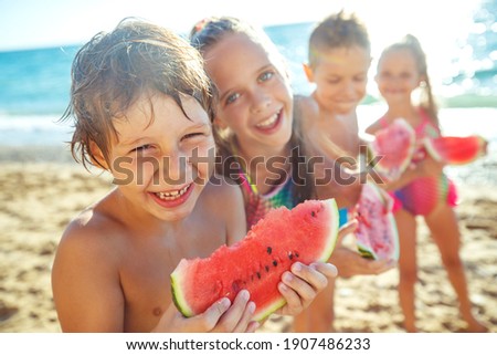 A group of children have fun playing at the sea. Children in bathing suits. Friends holding hands and running on the beach. High quality photo. Royalty-Free Stock Photo #1907486233