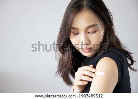 Asian woman receiving getting vaccinated immunity with bandage on her upper arm, concept of innoculation, vaccination, vaccine volunteer or vaccinated patient Royalty-Free Stock Photo #1907489512