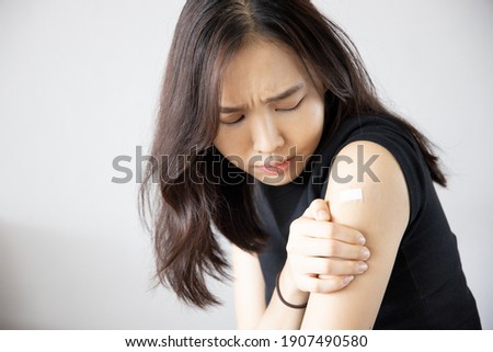 Asian woman receiving getting vaccinated immunity with bandage on her upper arm, concept of inoculation, vaccination, side effects of vaccine Royalty-Free Stock Photo #1907490580
