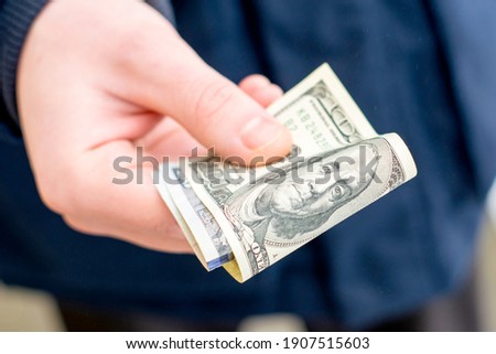 the hand holds out several hundred dollar bills folded in half. High quality photo