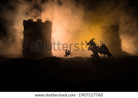 Fantasy battle scene with dragons attacking a medieval castle at night. Battle between dragon and heroic soldiers. Creative table decoration. Selective focus