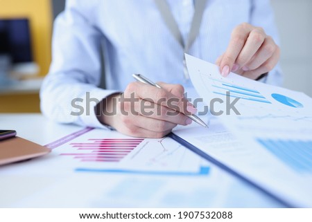 Woman signing document with graphs with ballpoint pen closeup. Business administration concept Royalty-Free Stock Photo #1907532088