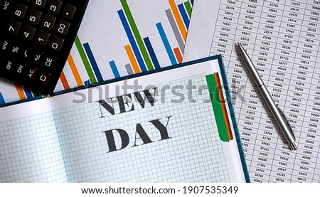 Closeup of notebook with text NEW DAY on chart background.