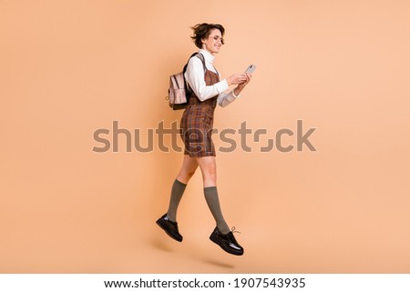 Full size profile photo of optimistic short hairdo girl jump run look telephone wear dress socks shoes isolated on peach background