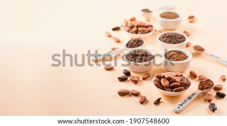 Bowls with aromatic raw cocoa beans, cocoa nibs, organic cocoa powder on natural beige paper background, copy space. Super brain food concept. Royalty-Free Stock Photo #1907548600