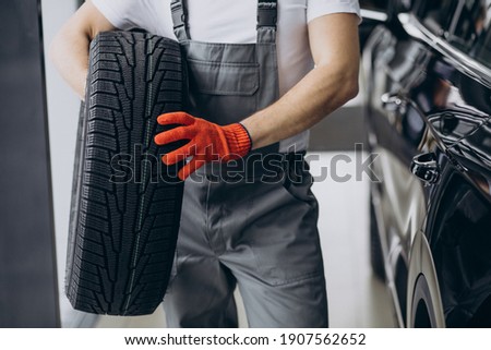 Mechanic changing tires in a car service Royalty-Free Stock Photo #1907562652