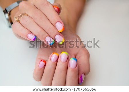 Hands of a young woman with a manicure. The nails are covered with gel polish with colored French. Royalty-Free Stock Photo #1907565856