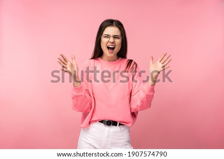 Photo of attractive young woman in glasses screaming yelling angry wear casual pink t-shirt white pants isolated pink color background