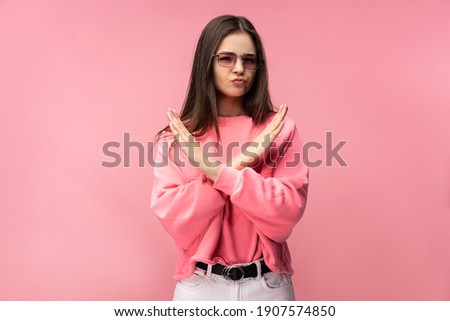 Photo of attractive young woman in glasses, not allow to do something, dislike and disagree. Wears casual pink t-shirt white pants isolated pink color background Royalty-Free Stock Photo #1907574850
