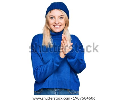 Young caucasian woman wearing wool winter sweater and cap praying with hands together asking for forgiveness smiling confident. 