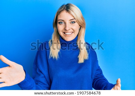 Young caucasian woman wearing casual winter sweater looking at the camera smiling with open arms for hug. cheerful expression embracing happiness. 