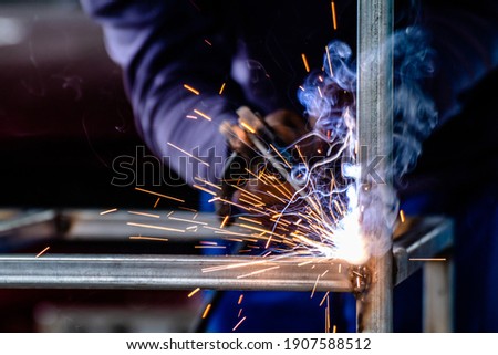 welder and welding sparks, construction and metal work industrial concept, metal welding with sparks, laborer or labor day concept Royalty-Free Stock Photo #1907588512