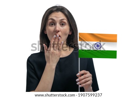 Happy young white woman holding flag of India and covers her mouth with her hand isolated on a white background.