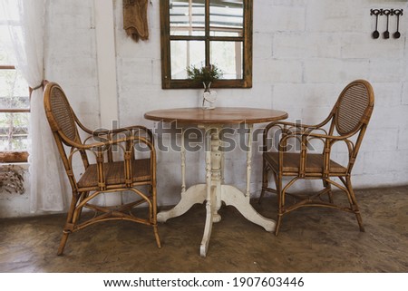 Cane furniture set of two chairs and a coffee table against a white wall 