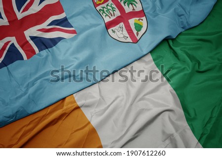 waving colorful flag of cote divoire and national flag of Fiji . macro