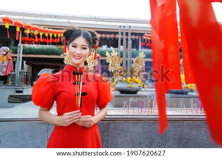 A Chinese woman in a red dress is burning incense.
