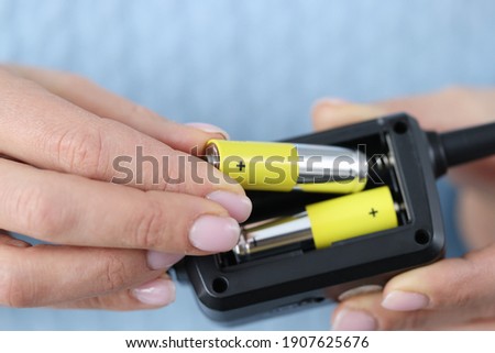 Female hands inserting batteries into remote closeup. Repair of household appliances concept Royalty-Free Stock Photo #1907625676