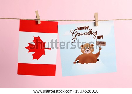 Happy Groundhog Day greeting card and Canada flag hanging on pink background