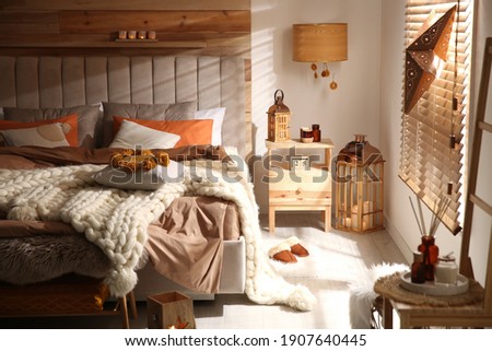 Cozy bedroom interior with knitted blanket and cushions Royalty-Free Stock Photo #1907640445