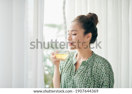 women standing in front of windows and holding tea cup in the morning Royalty-Free Stock Photo #1907644369
