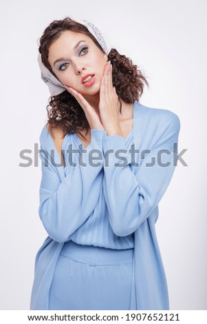 High fashion photo of a beautiful elegant young woman in a pretty blue suit, pants, top, cardigan, sneakers, head scarf posing over white background. Studio Shot. Portrait