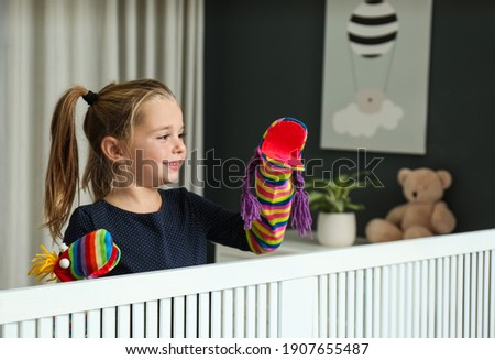 Cute little girl performing puppet show at home Royalty-Free Stock Photo #1907655487