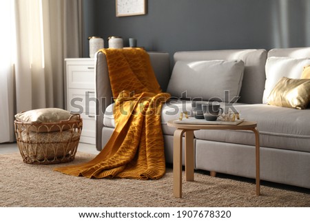 Stylish sofa with soft plaid in room. Idea for interior design Royalty-Free Stock Photo #1907678320