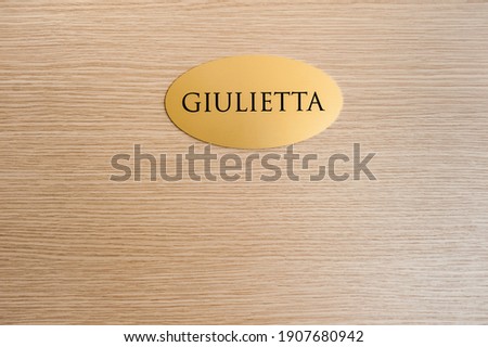 Gold name plate engraved with the name Giulietta (translation: Juliet) on wooden door of hotel room