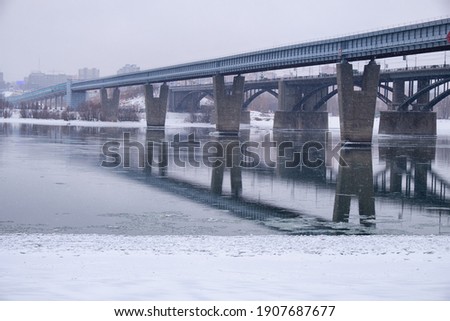Photo  of the frozen Ob River with road and subway bridges on a winter snowy day. Novosibirsk, Siberia, Russia.