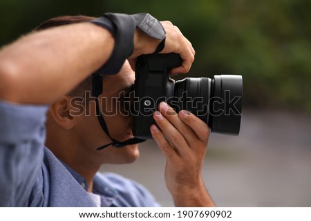 Photographer taking picture with professional camera outdoors, closeup