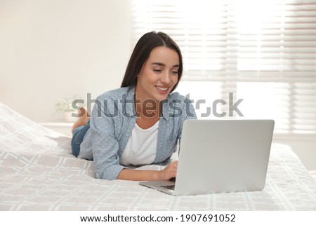 Woman using laptop for search on bed at home
