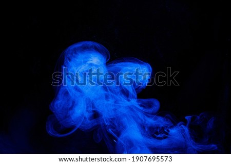 Art photo of blue smoke moves on black background. Beautiful swirling smoke.
