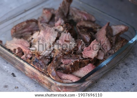 Sliced medium rare ostrich steak inside a glass container. This photo has selective focus. 