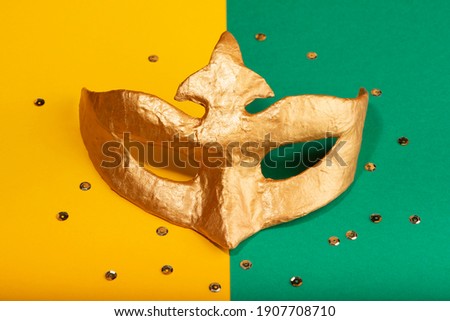 Golden mask on green and yellow background. Mardi gras and Fat Tuesday carnival concept.