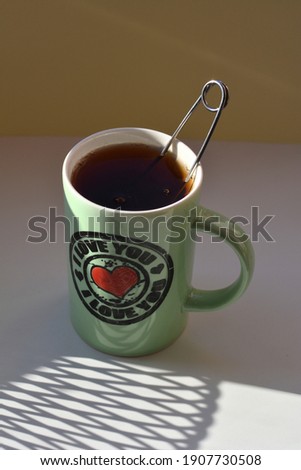 cup of tea with red heart in sunlight and shadows on a white background
