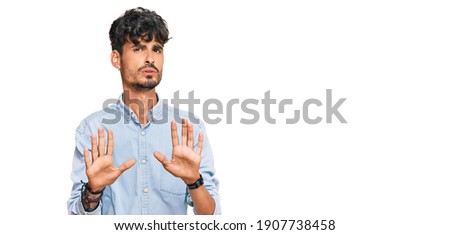 Young hispanic man wearing casual clothes moving away hands palms showing refusal and denial with afraid and disgusting expression. stop and forbidden. 