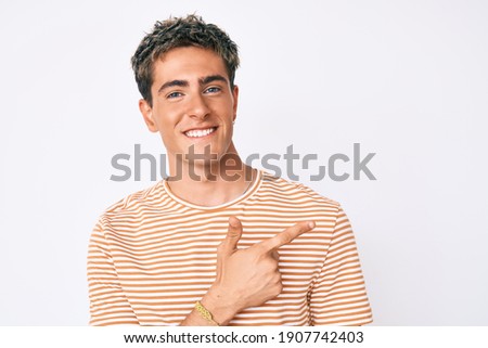 Young handsome man wearing casual clothes cheerful with a smile of face pointing with hand and finger up to the side with happy and natural expression on face 