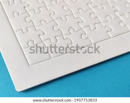 Close-up of blank white jigsaw puzzle on blue background