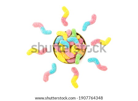 Creative flat lay made of colored sugar coated gummy worms sun shaped around a tin box isolated on white