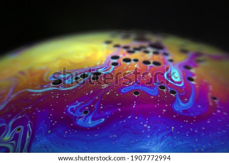 Macro picture of half soap bubble on black ground look like abstract psychedelic color planet in space	