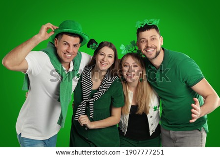 Happy people in St. Patrick's Day outfits on green background