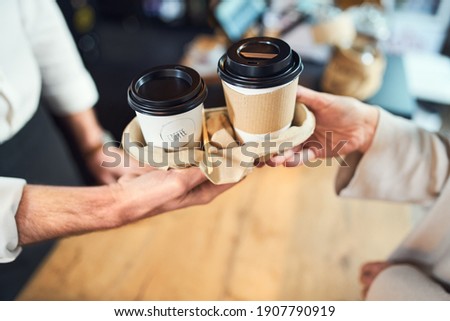 Take away coffee. Closeup of barista serving takeaway cups of coffee Royalty-Free Stock Photo #1907790919