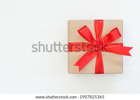 Gift box wrapped with red ribbon on white wood background