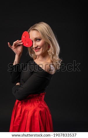 Girl holds a heart at eye level Valentine valentine background, happiness, on the floor hearts romance wedding. the banner form. love festive, black in red dress girl, barefoot
